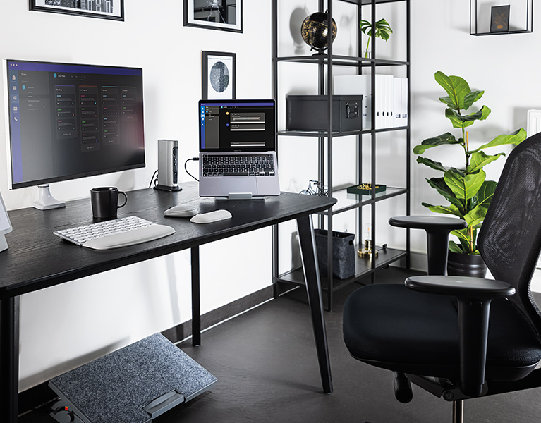 Ergonomiczna konfiguracja domowego biura z klawiaturą, myszką, uchwytem na monitor i podstawką pod stopy firmy Kensington.