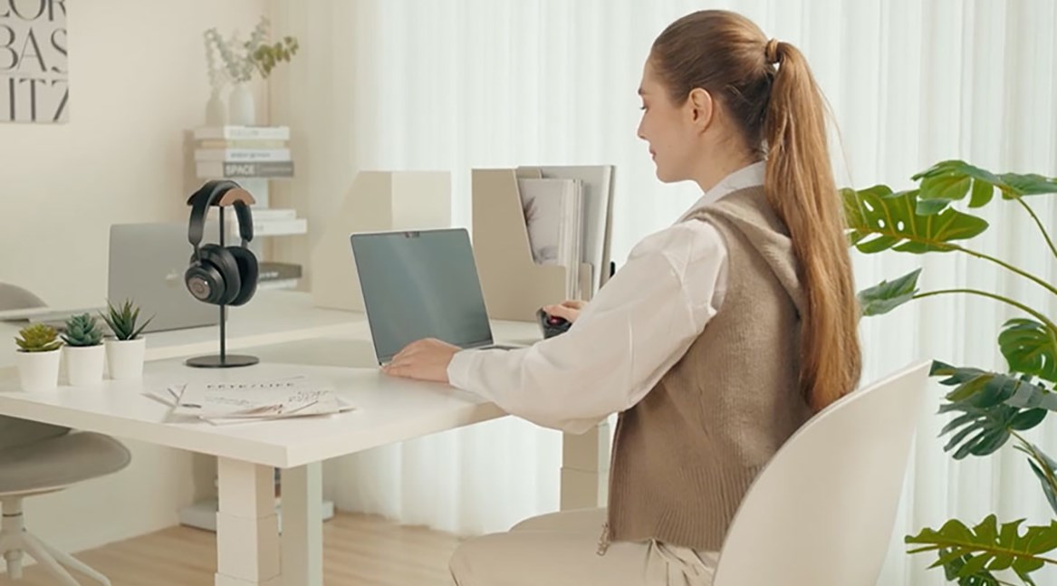 Woman placing the Kensington MagPro™ privacy screen on a laptop.