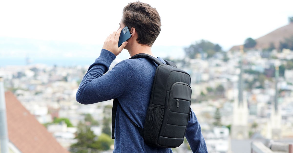 A person with a Kensington backpack standing on a balcony with a cityscape in the background.