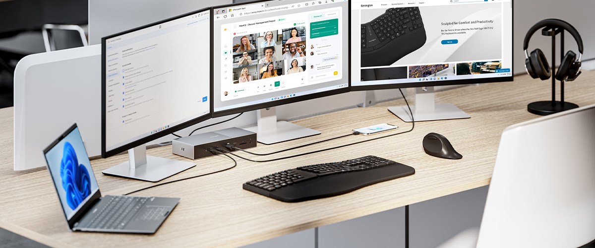 A professional desk setup with a laptop, two monitors, a keyboard, and a mouse connected via a Thunderbolt docking station. Headphones sit on a stand, showcasing an organized and ergonomic workspace.