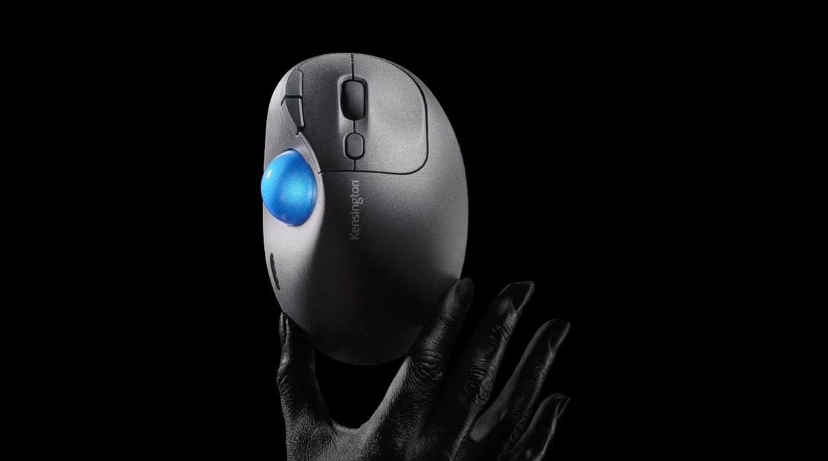 En Ergo-trackball som holdes av en hånd på en mørk bakgrunn.