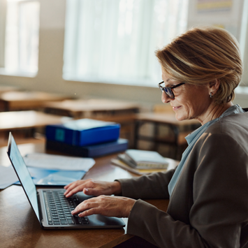 Woman working from the classroom using her laptop.