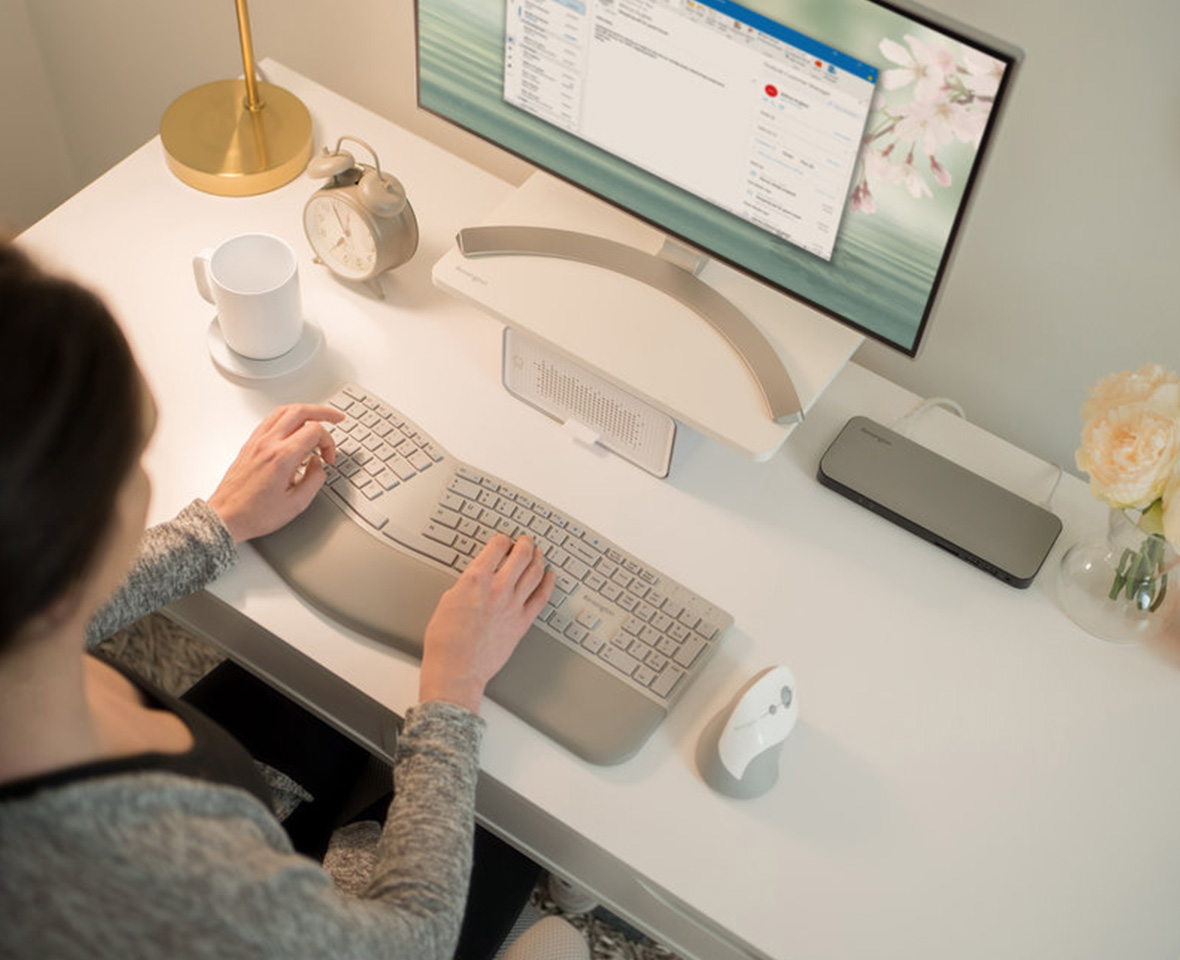 Femeie care tastează pe o tastatură ergonomică la biroul de acasă.