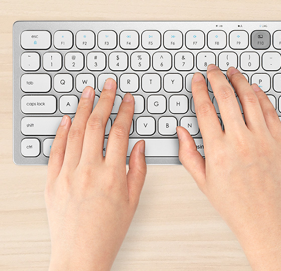 在现代工作空间中使用肯辛通 Kensington 多设备无线便携键盘的双手的特写镜头。