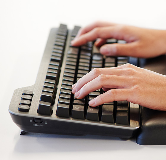 双手在肯辛通 Kensington MK7500 QuietType™ Pro 静音机械键盘上打字的特写镜头。