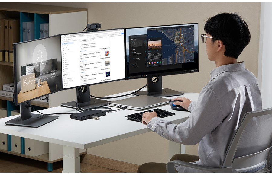 Man at desk using triple monitor connected to Kensington USB-C Driverless Docking Station.