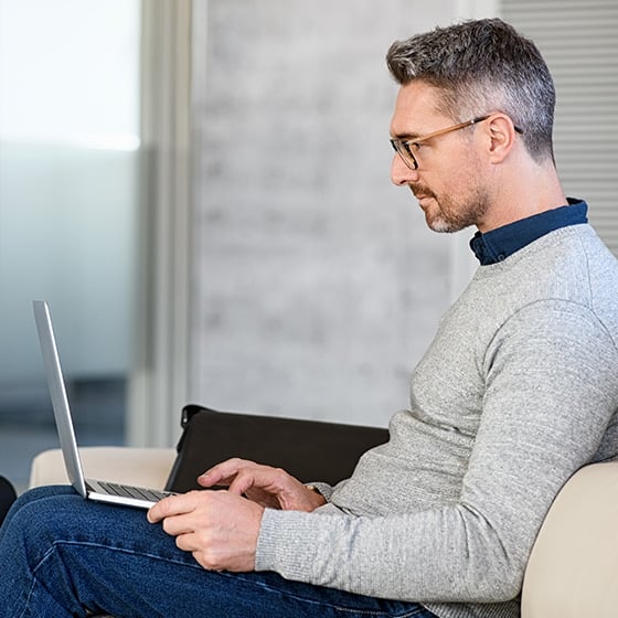 Man sitting with laptop using a Kensington MagPro Elite Privacy Screen Filter.