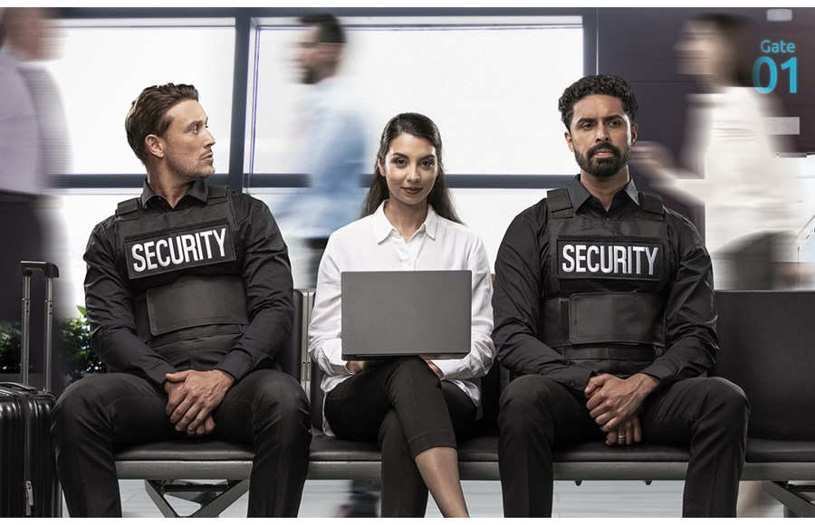 Woman on bench sitting in between two security guards using her laptop with a Kensington privacy screen.