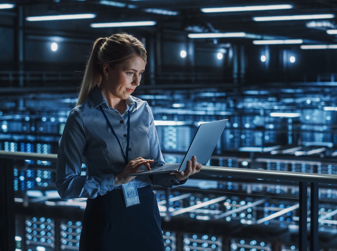 IT Woman holding up a laptop and working on it.